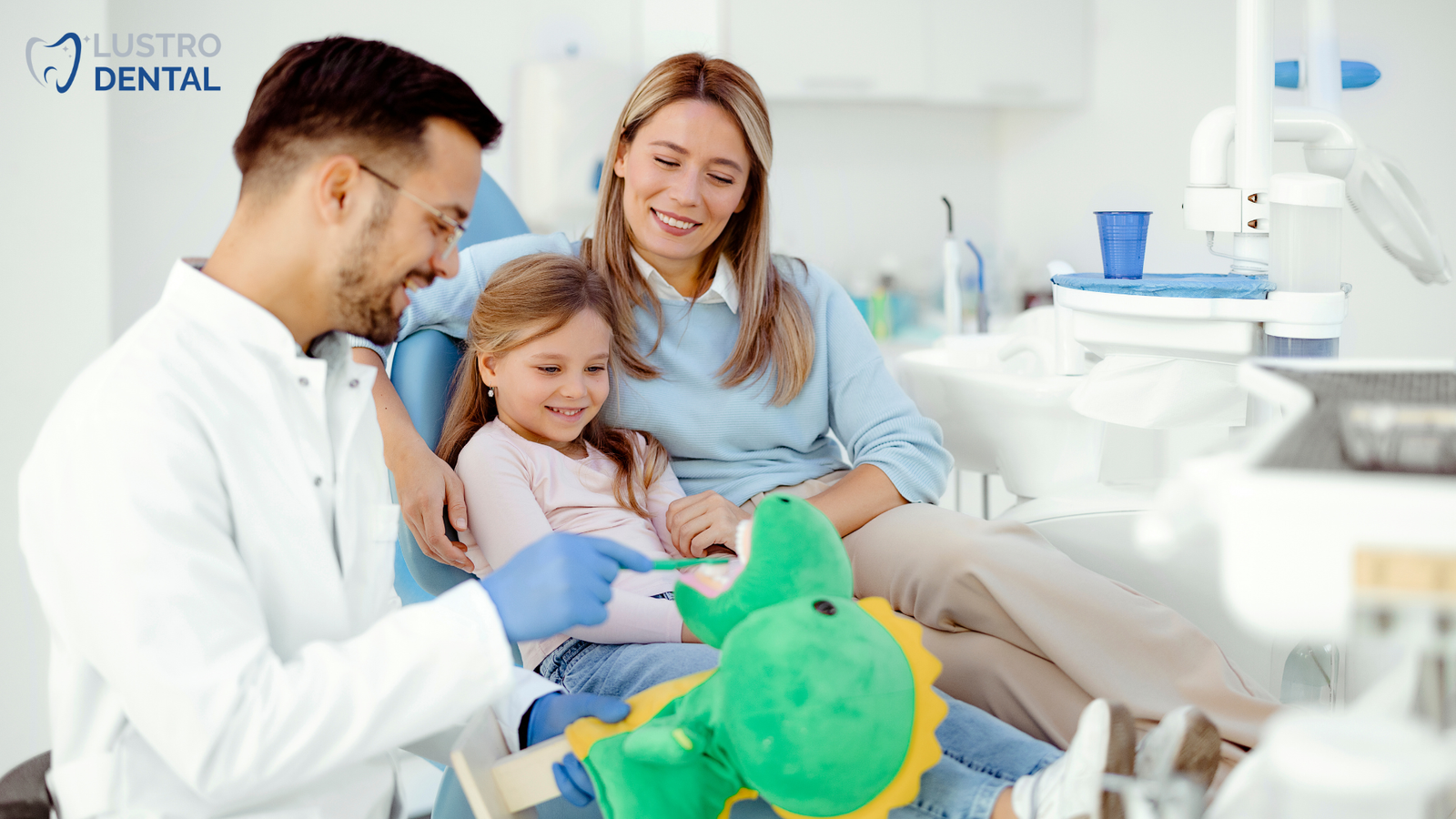 A dental hygienist greets a baby at eye level, establishing a friendly connection before the examination.