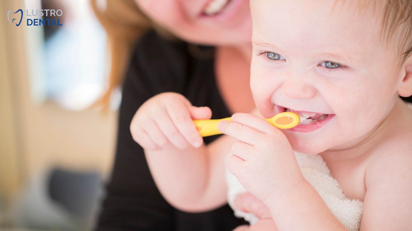 A dentist discusses home care strategies with a parent while the baby explores a child-friendly dental mirror.